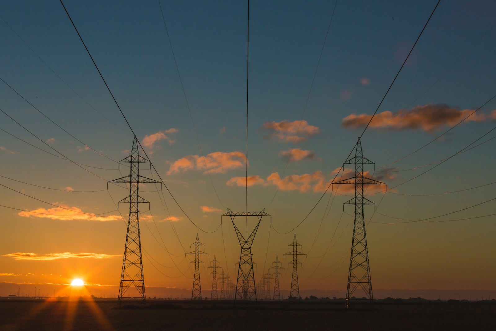 High voltage transmission lines crossing an energy landscape at sunset